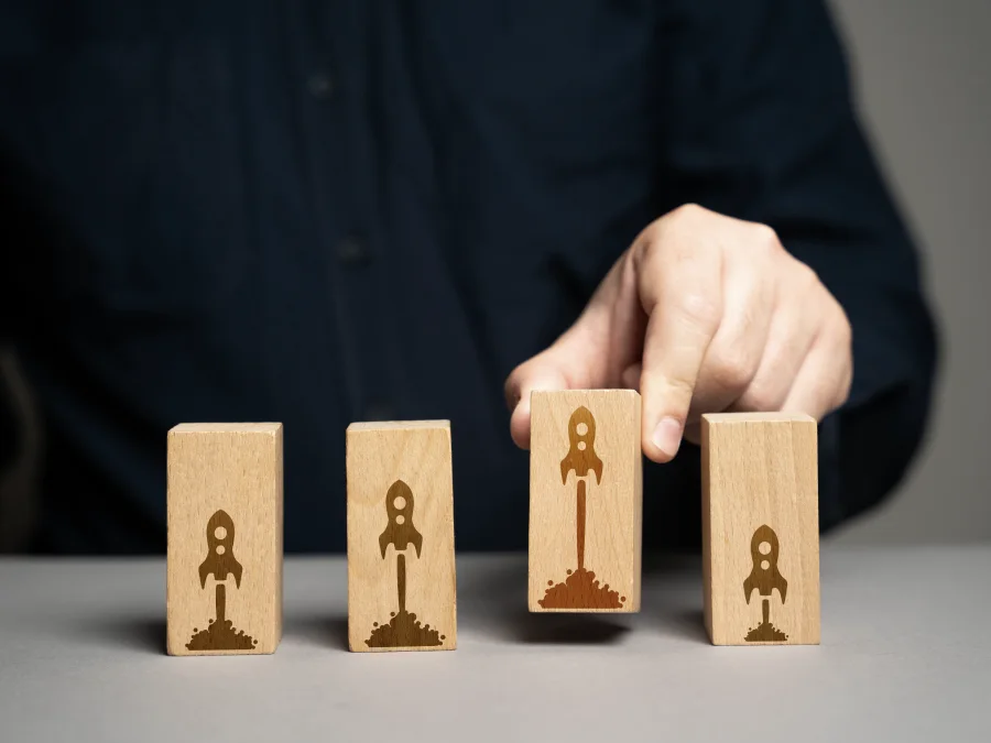 Hand choosing a wooden block printed with a launching rocket