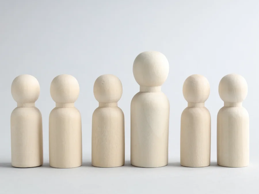 Row of wooden figures with one taller leader figure in the centre